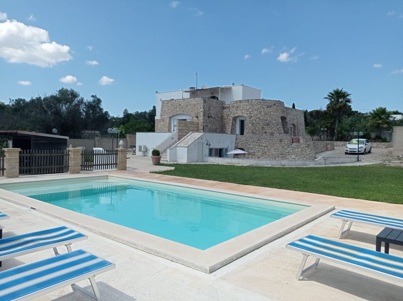 La piscina privata con la villa in pietra alle spalle